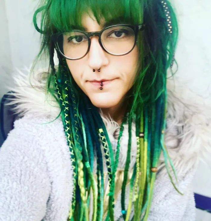 Stephanie Thomas with vivid green hair, reflecting her creative specialty-color identity